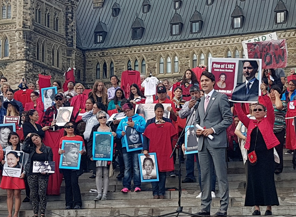 Maggie Cywink, right, holds up a sign behind Canadian Prime Minister Justin Trudeau as he speaks during a vigil in support of missing and murdered Indigenous women in Ottawa on Oct. 4, 2017. Photo: Courtesy of Maggie Cywink