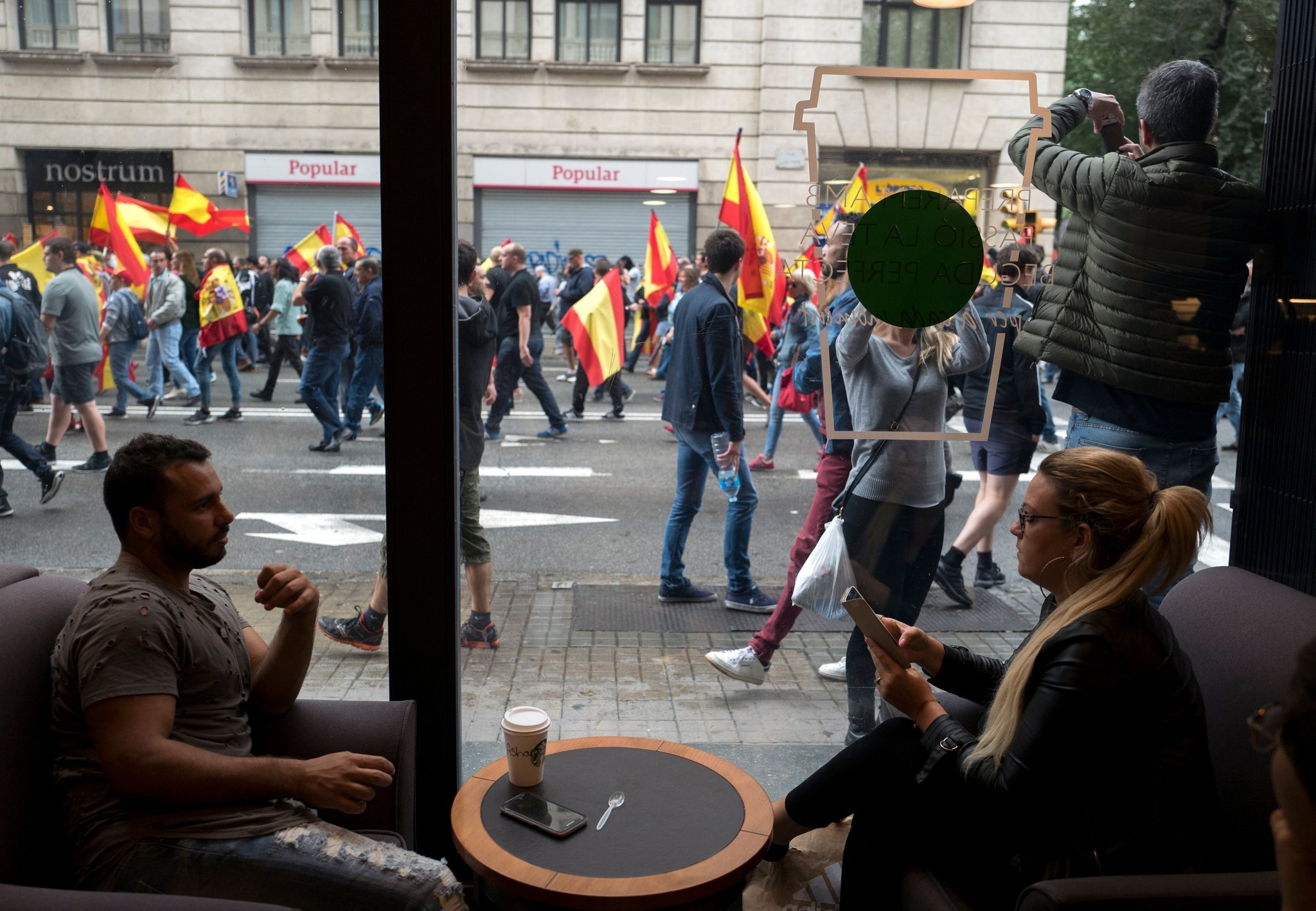 Demonstrators protesting against the Catalonia referendum passed a cafe in Barcelona on Sunday. Credit Jim Hollander/European Pressphoto Agency