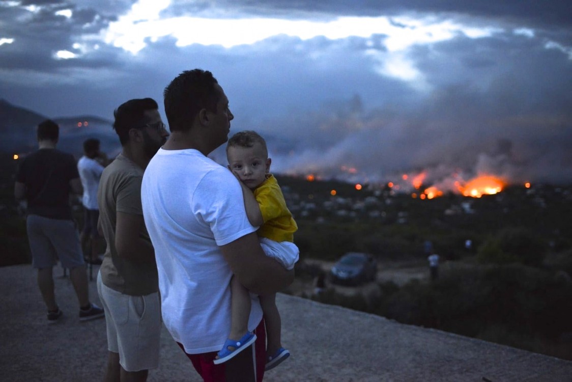 Residents watch as fires burn into the city of Rafina, near Athens, on July 23. The blazes moved quickly through the drought-parched area, killing more than 80 people. Credit: Angelos Tzortzinis/AFP/Getty Images