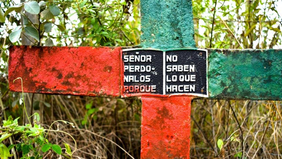 A cross on the side of the road painted in the colours of the Nasa indigenous people, reads, “Lord forgive them, fore they know not what they do.” Miranda, Cauca, Colombia. Photograph: Tom Laffay for the Guardian