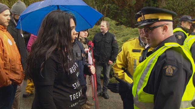 An anti-pipeline protester at a Kinder Morgan terminal in Burnaby speaks with a RCMP officer on Saturday, March 24, 2018. (CBC)
